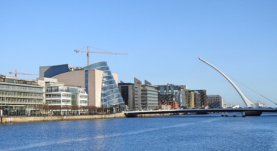 10th December 2021, Dublin, Ireland. Selective focus on the River Liffey, with background office blocks including Dublin Convention Centre, PwC Ireland and Samuel Beckett Bridge in Dublin's Docklands.