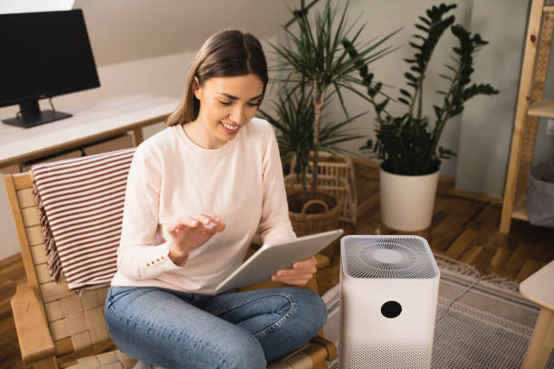 istock Young woman turning on air purifier using a digital tablet 1360351265