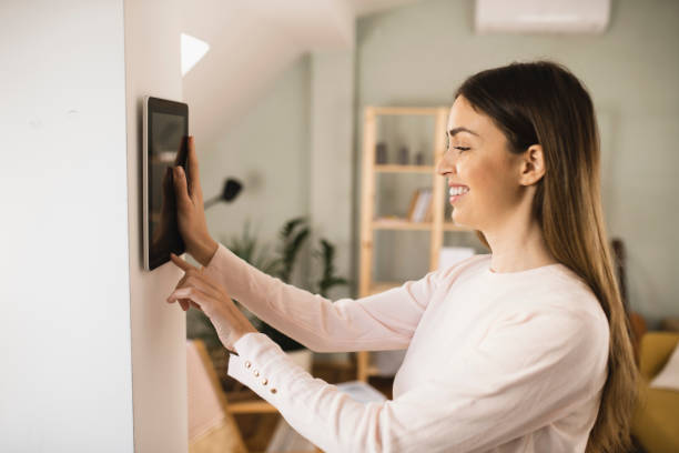 istock Young woman adjusting a smart house system 1360351270