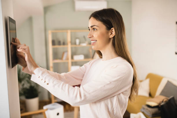 istock Happy young woman adjusting a smart system at her house 1360351271