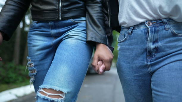 istock Two girlfriends holding hands walking together outside 1360355063
