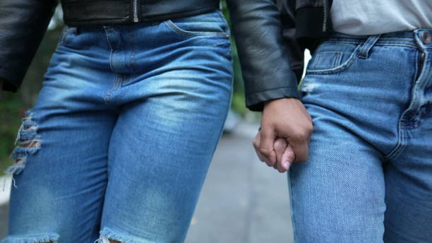 istock Two girlfriends holding hands walking together outside 1360355590