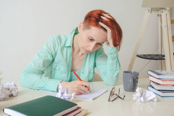 istock A young woman at a desk makes notes on paper with a red pencil. 1360357598