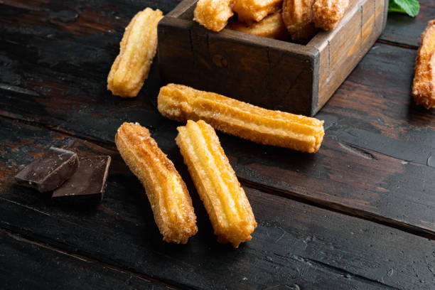 istock Typical Spanish snack  churros, fried-dough pastry served  usually with chocolate caramel hot sauce, on old dark  wooden table background 1360358719