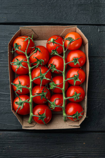 istock Ripe cherry tomatoe in tray, on black wooden table, top view 1360358849