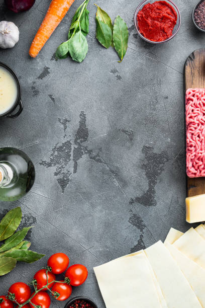 istock Empty space clean Frame  The concept of cooking lasagna. Italian Ingredients, lasagna sheets meat herbs tomatoes, bechamel sauce, on gray stone background, top view, flat lay, with copy space for text 1360360062