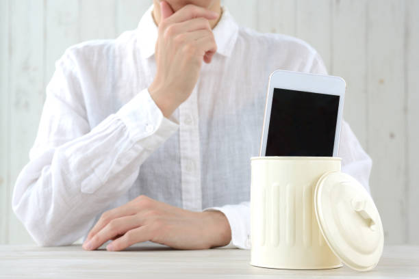 istock Thinkng woman and smart phone thrown away in dust box 1360363562