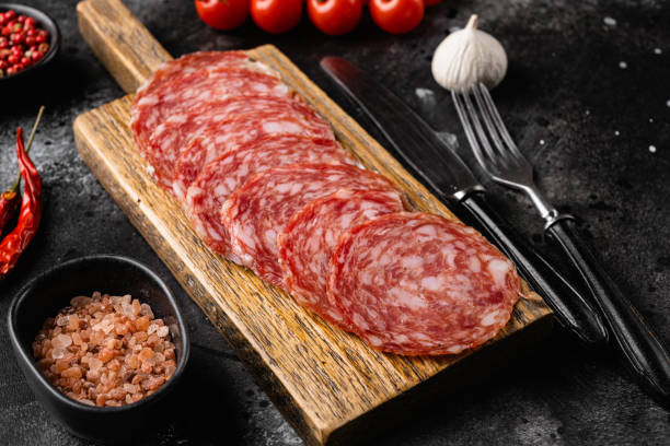 istock Salami smoked sausage, on black dark stone table background 1360364568