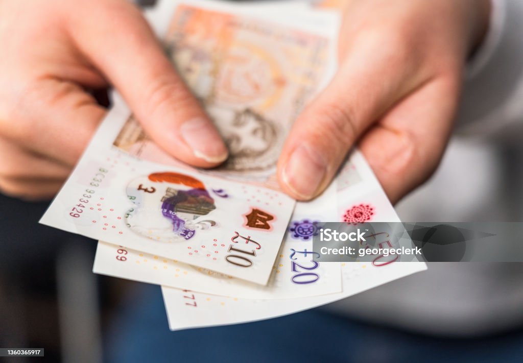 British banknotes Close-up of a woman holding modern polymer ten, twenty and fifty pound notes. Currency Stock Photo