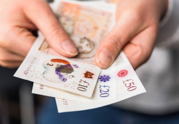 British banknotes Close-up of a woman holding modern polymer ten, twenty and fifty pound notes. pound symbol stock pictures, royalty-free photos & images