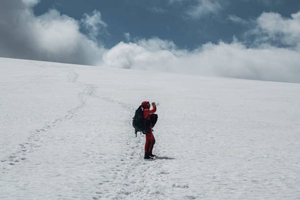 istock Male climber drinks water on a snowy mountainside while climbing. 1360366046