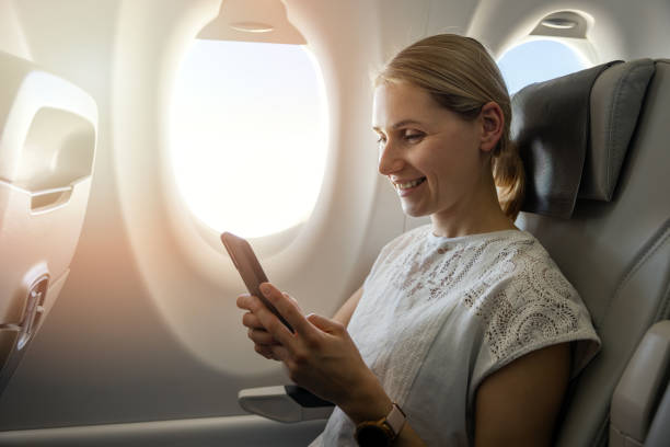 jeune femme utilisant un téléphone portable pendant le vol dans l’avion - telephone cabin photos et images de collection