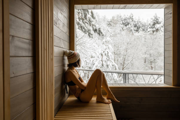 Woman resting in sauna with view on snowy nature