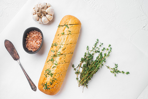 Baguette with parsley herbs butter set, on white stone table background, top view flat lay