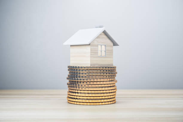 istock Creative house on golden coins stack. Light wooden background with mock up place. Mortgage, money and property concept. 3D Rendering. 1360372588
