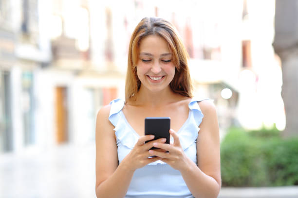 istock Happy female walking using smartphone in the street 1360381962