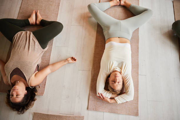 istock Young women doing breathing exercises on yoga mats 1360383086