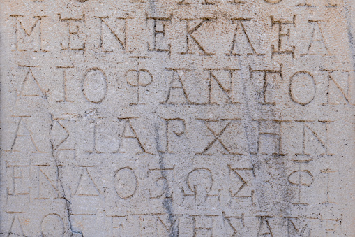 Ancient Greek inscriptions on stone in archeological ruin in ancient Greece site - design, background, texture, creative use