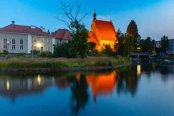 Panorama of Brick Gothic Bydgoszcz Cathedral with reflection in Brda River at night, Bydgoszcz, Poland