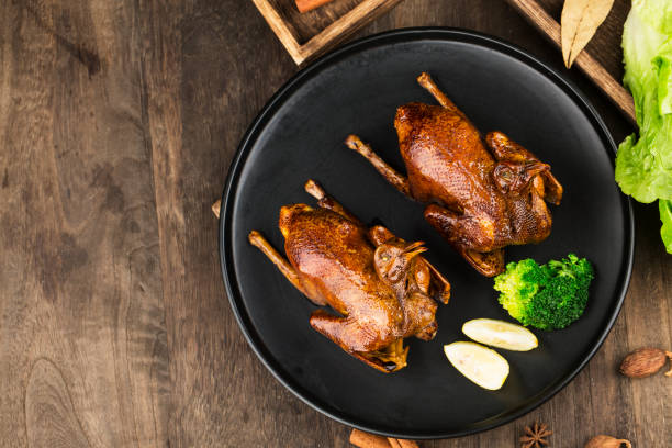 Traditional Cantonese roast pigeon on a and white porcelain plate Traditional Cantonese roast pigeon on a and white porcelain plate squab pigeon meat stock pictures, royalty-free photos & images
