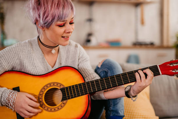 istock Woman playing acoustic guitar at home 1360388074