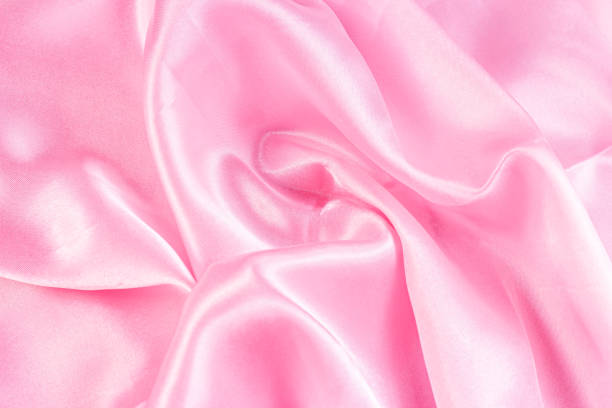 istock Light pastel pink color silk wavy textile pattern as a smooth textured background. Rose colored soft satin fabric drapery 1360388388