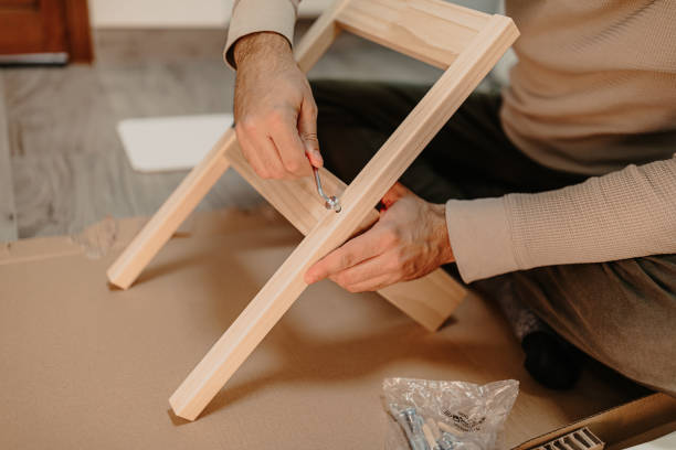 istock Skilled man assembles wooden furniture with a hex key 1360390583