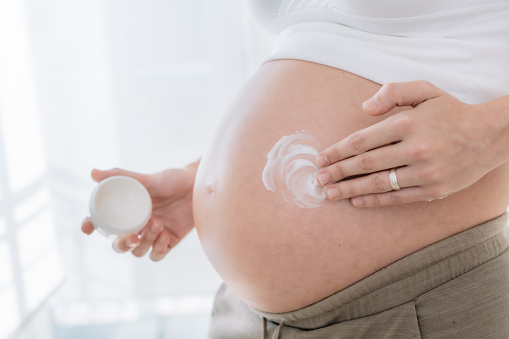 mano de mujer embarazada aplicando crema hidratante en la piel de su vientre para prevenir las estrías del embarazo. concepto de cuidado de la salud en el embarazo y cuidado de la piel photo