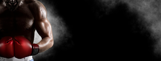 Man boxer in red gloves on black background. Sports banner. Horizontal copy space background