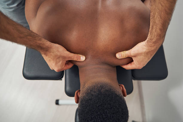 Skilled masseur giving his client trigger point massage Cropped photo of Caucasian professional massotherapist hands massaging African American patient neck black male massage stock pictures, royalty-free photos & images