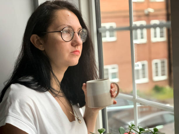 istock Young woman is drinking coffee by the window. Deep in thought 1360403291