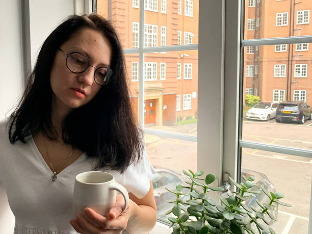 istock Young woman is drinking coffee by the window. Deep in thought 1360403331