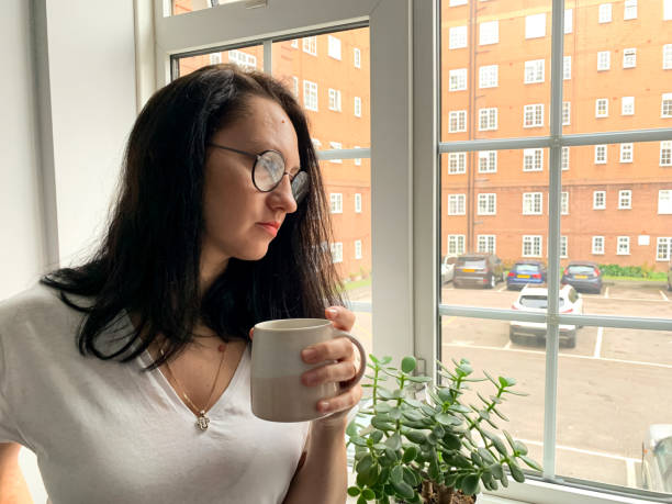 istock Young woman is drinking coffee by the window. Deep in thought 1360403342