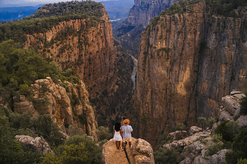 Tourist stylish couple standing on the edge of a cliff against the backdrop of a gorge. Amazing Tazi Canyon ,Bilgelik Vadisi in Manavgat, Antalya, Turkey. Greyhound Canyon, Wisdom Valley.