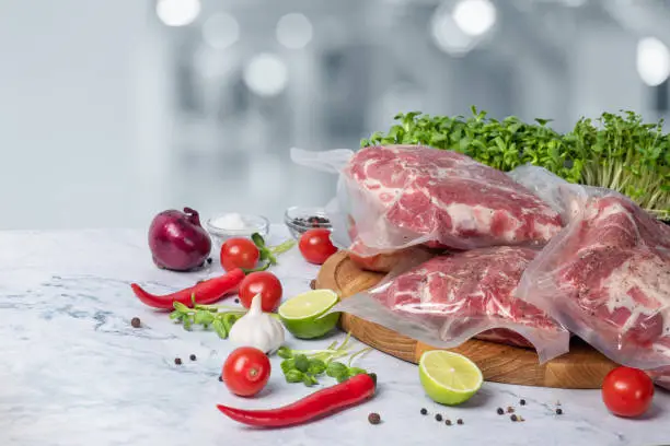 Vacuum sealed meat and vegetables on blurred background.
