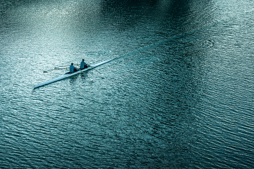 two male rowers sculling on river