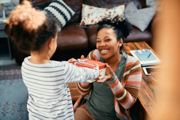 heureuse mère afro-américaine recevant des cadeaux de sa fille à la maison. - gift mothers day birthday giving photos et images de collection