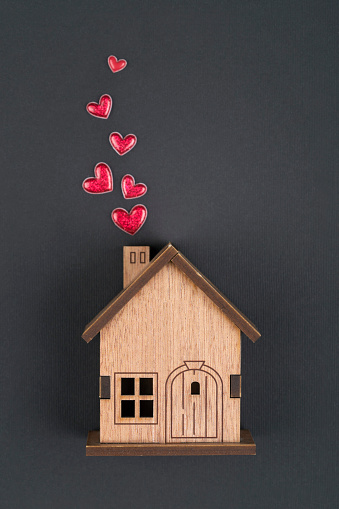 Wooden house  and  red heart shape on black background with copy space