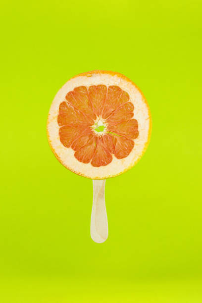 istock Grapefruit icecream with wood stick on light green background. Creative summe fruity popsicle sticks. 1360408690