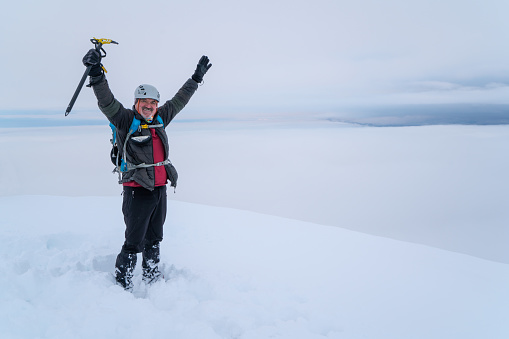 Elderly climber is happy and proud of himself after a hard climbing activity in the peak.