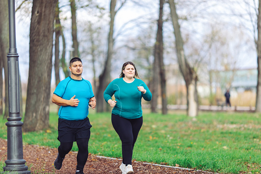 Plus size couple training and running outdoors. They are doing some cardio exercises for weight loss after quarantine period