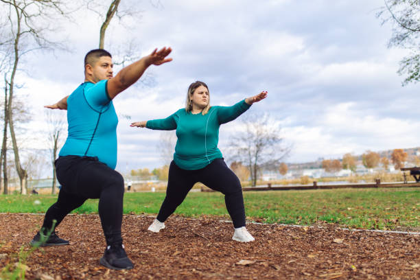 People with overweight problem exercising in city park Plus size couple training and running outdoors. They are doing some cardio exercises for weight loss after quarantine period body positive couple stock pictures, royalty-free photos & images