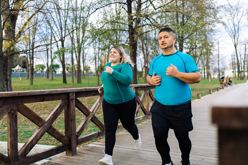 Plus size couple training and running outdoors. They are doing some cardio exercises for weight loss after quarantine period