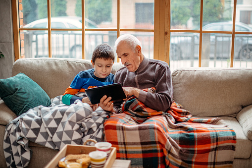 Boy showing something on digital tablet to his grandfather