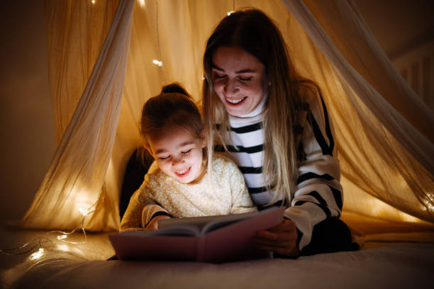 istock Mother and child reading book in bed before going to sleep 1360435575
