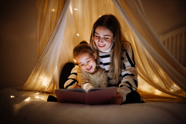 istock Mother and child reading book in bed before going to sleep 1360435623