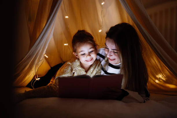istock Mother and child reading book in bed before going to sleep 1360435652
