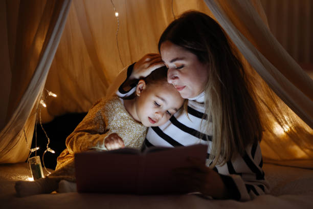 istock Mother and child reading book in bed before going to sleep 1360435692