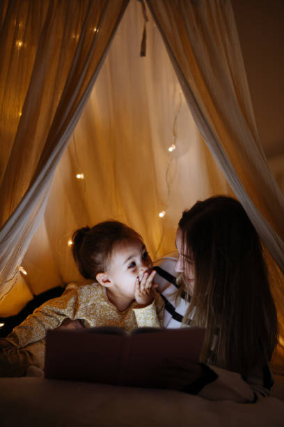 istock Mother and child reading book in bed before going to sleep 1360435719