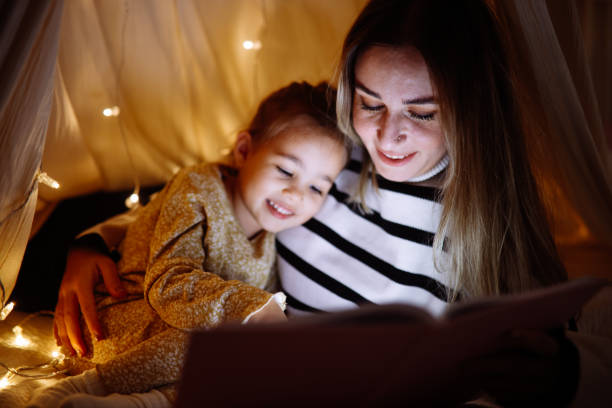 istock Mother and child reading book in bed before going to sleep 1360435739